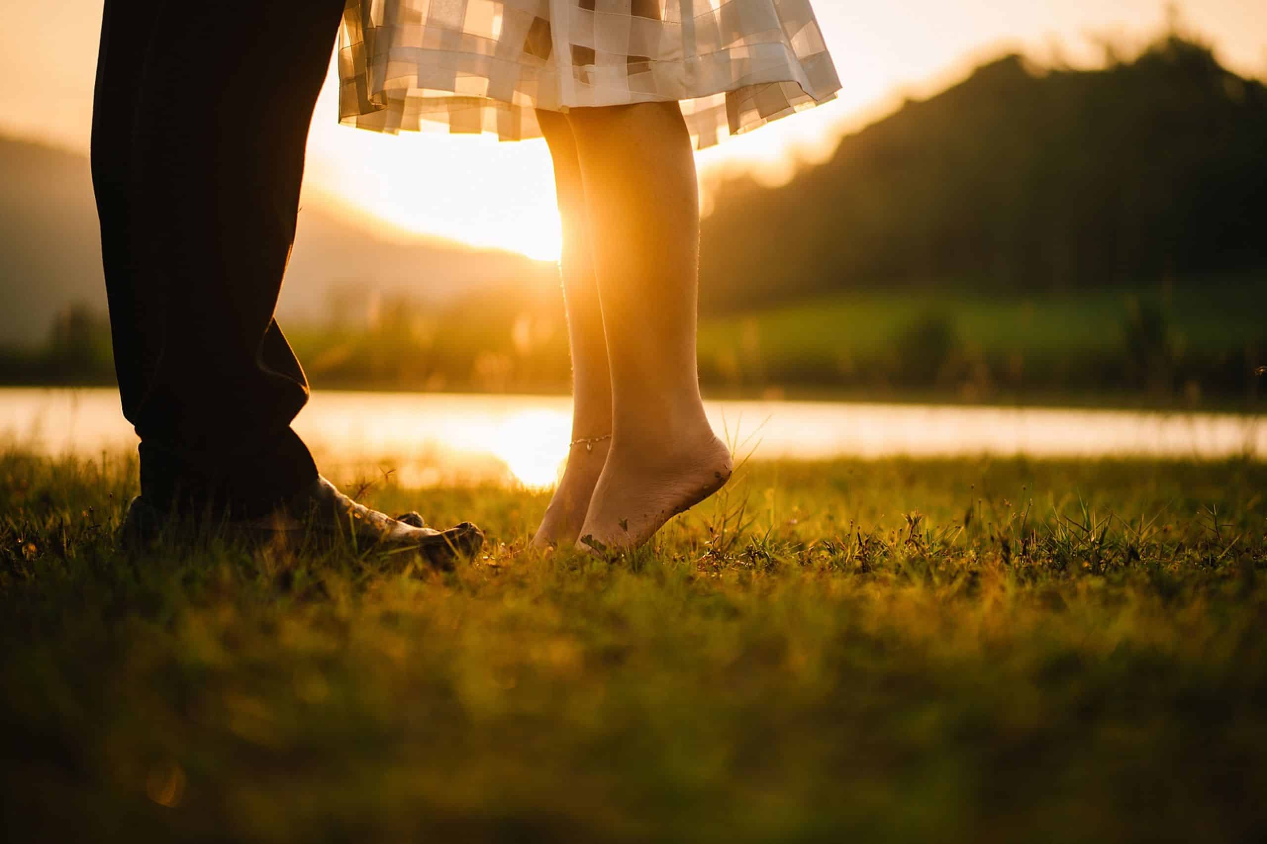 the feet of a man and woman standing in a field