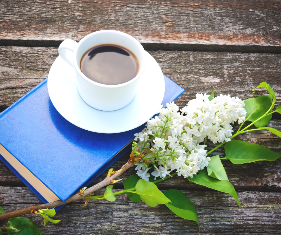 a blue book with a cup of coffee and some white flowers
